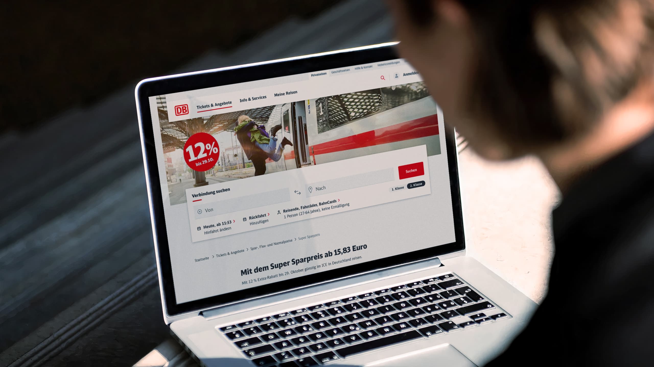 Person sitzt vor einem Laptop und besucht die Buchungsseite der Deutschen Bahn.